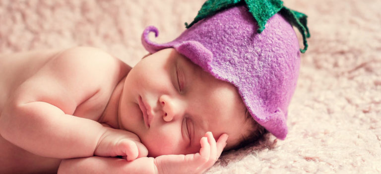 帽子を被ってすやすやと眠る裸の赤ちゃん